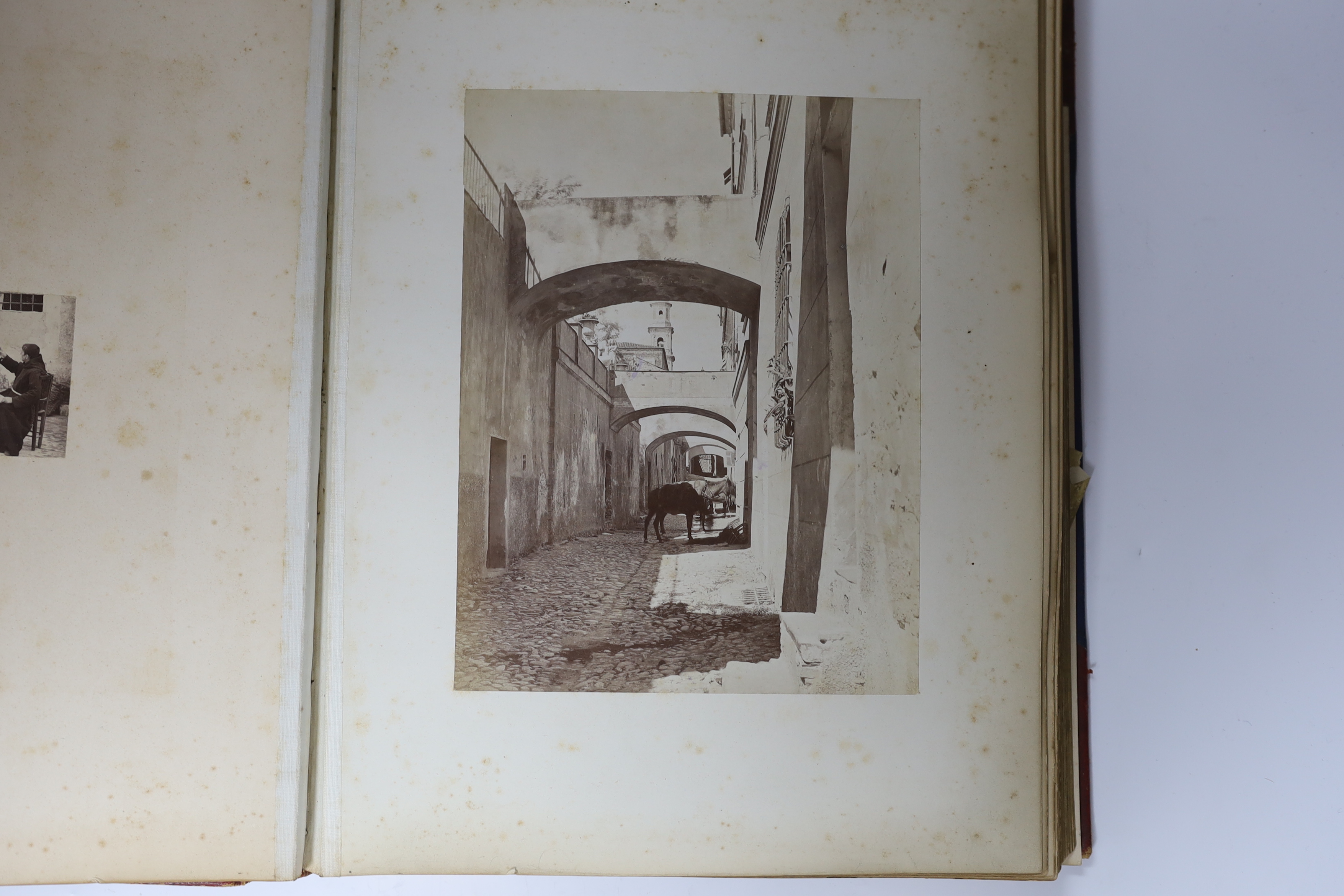 A late 19th century album of black and white photographs of views, principally in Europe and including family groups and portraits, country house interiors et., folio, half red morocco, 37 x 27cms